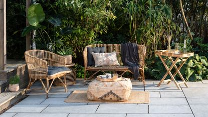 Exotic themed garden furniture made of cane on patio next to leafy foliage
