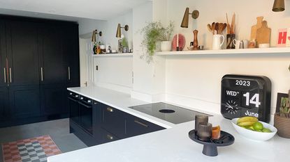 Run of grey kitchen units with white worktops and open shelf instead of wall cabinets